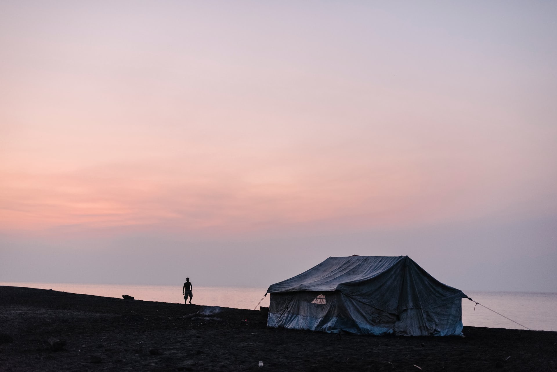 A man watches the sun set over Ambae Island. Communities from villages in the mountain were provided with tents for temporary housing when they evacuated to safer ground along the coastline in April due to volcanic activity. Photograph: Alana Holmberg for the Guardian